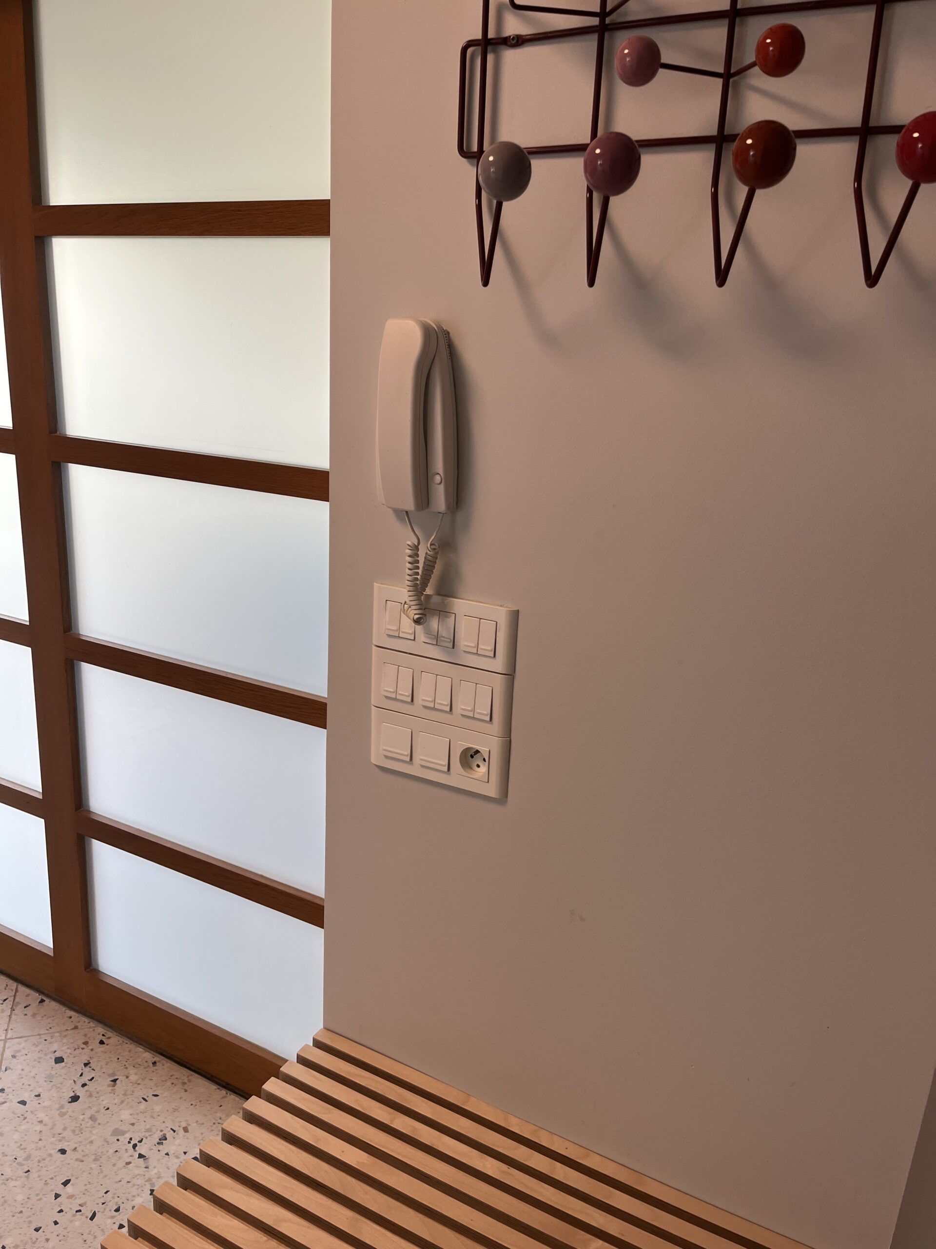 Avant rénovation à Binic : rangées de commandes murales et ancien interphone dans l’entrée